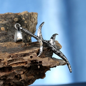 Vintage punk dagger pendant in aged titanium steel on a natural bark background