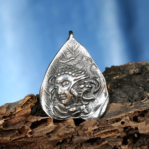 Vintage stainless steel Buddha pendant with leaf texture on rustic wood background