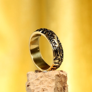 Gros plan sur une bague dorée en acier inoxydable avec motif de montagne et texture