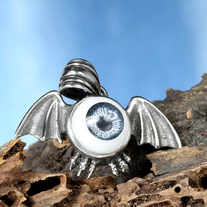 Macro detail of retro punk bat wings pendant with a blue eye iris on textured wood