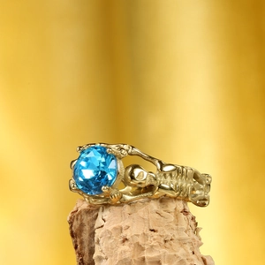 Dettaglio anello teschio gotico con pietra blu incastonata su base in legno