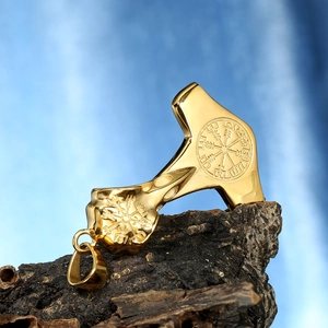 Macro del ciondolo Mjolnir dorato con incisione Vegvisir su uno sfondo di legno rustico