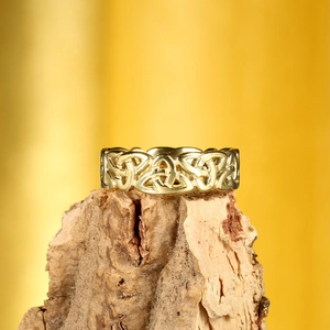 Detailed view of hollow gold Viking Celtic knot ring resting on a natural wood base