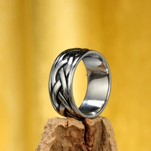 Vintage woven Viking steel ring for men on a natural wood base with yellow background