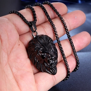 Détail du pendentif tête de lion noir aux gravures précises sur une chaîne sombre