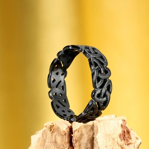 Close-up of black viking celtic knot ring on wood base with warm yellow backdrop