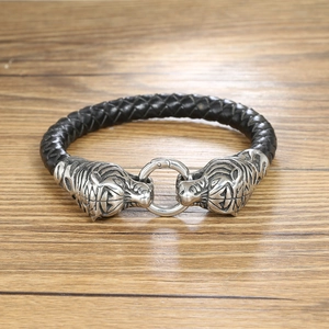 Detailed macro shot of men's black braided leather bracelet with twin tiger head charms