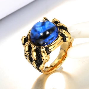 Macro shot of gold punk dragon claw ring featuring a mystical round blue gemstone inlay