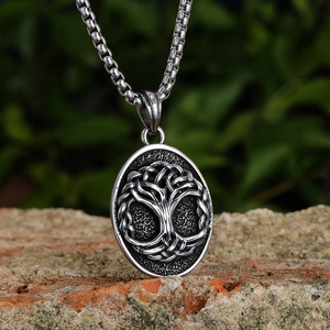 Vintage silver Tree of Life pendant necklace in Nordic style on a red brick background
