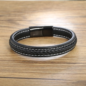 Detail of black woven leather bracelet with white stitching and magnetic metal clasp