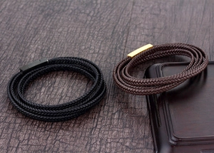 Détail de bracelets en cuir tressé multicouches avec fermoirs magnétiques sur bois