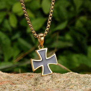 Détail du pendentif croix pattée avec émail gris sur une chaîne à mailles gourmette dorée