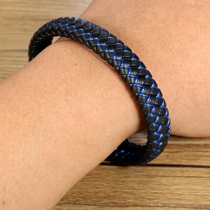 Détail du bracelet en cuir tressé noir avec accents bleus porté au poignet d'un homme