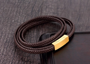 Détail d'un bracelet multicouche en cuir tressé marron avec fermoir magnétique doré
