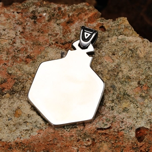 Silver Nordic Viking hexagon pendant in polished titanium steel on a natural rock surface