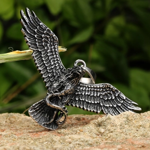 Pendentif aigle en acier inoxydable avec motif serpent sur un fond de pierre rustique