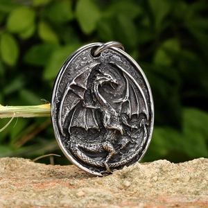 Vintage stainless steel dragon pendant with relief carving on a rustic stone background