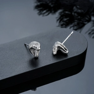 Close-up of vintage silver snake head earrings with detailed scales and gothic style