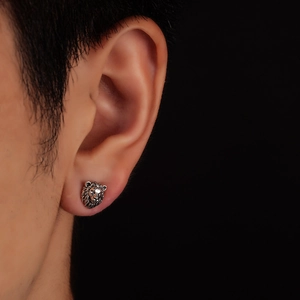 Gros plan d'un clou d'oreille tête de lion argenté vintage avec texture de crinière