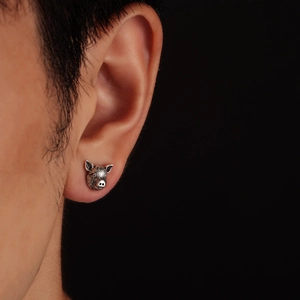 Close-up of vintage silver pig stud earring showing intricate texture and oxidized finish