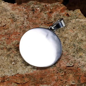 Macro detail of a round silver stainless steel pendant with a smooth mirror finish