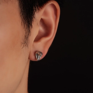 Close-up of a silver cobra snake stud earring with detailed scales on a male model