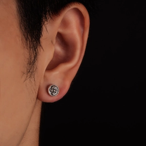 Gros plan d'une boucle d'oreille joker gothique en argent vieilli sur le lobe
