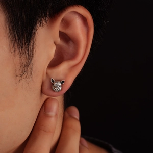 Detailed close-up of realistic pig stud earring with vintage silver finish on a model's ear