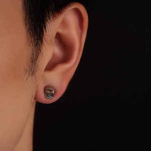 Détail macro d'une boucle d'oreille tête d'aigle en argent vieilli sur modèle