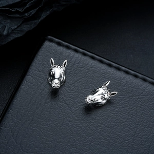 Macro detail of silver horse head stud earrings with vintage oxidized finish on leather