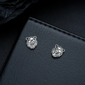 Gros plan sur des boucles d'oreilles tête de lion argentées sur cuir noir texturé