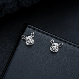 Detailed macro view of vintage silver pig stud earrings with realistic textured finish