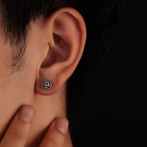 Gros plan d'un clou d'oreille masque de clown en argent oxydé style punk vintage