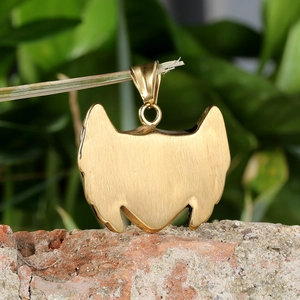 Close-up of golden knight shield pendant with brushed texture hanging on a branch