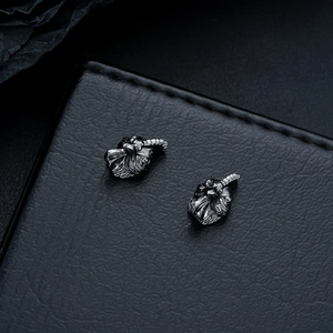 Macro shot of dark grey rooster studs with vintage texture on black leather background