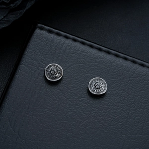 Detailed macro view of vintage silver lion head stud earrings with a circular dotted border