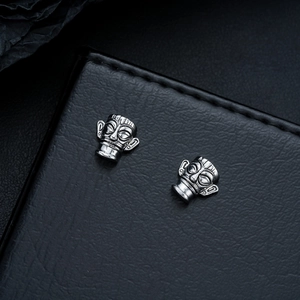 Macro view of retro silver Sanxingdui mask stud earrings on black leather display