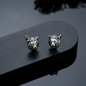 Détail macro de boucles d'oreilles tête de lion en argent vintage au fini texturé