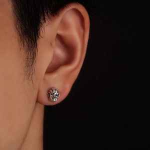 Close-up of vintage mask stud earring in oxidized silver on male model's ear