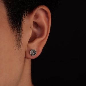 Macro shot of silver lion head magnetic stud earring with vintage embossed metal detail