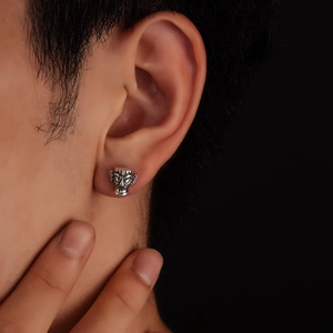 Detailed view of vintage silver Sanxingdui mask stud earring worn on earlobe