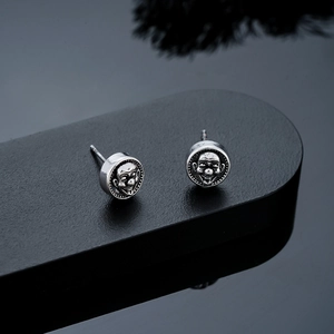 Détail macro de boucles d'oreilles joker gothique en argent vintage gaufré