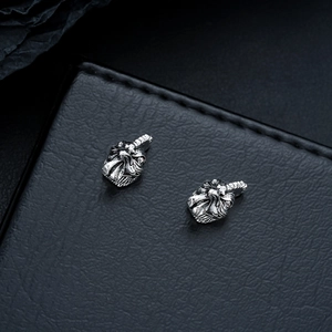 Detailed view of silver rooster head earrings with vintage punk style textures