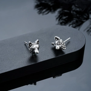 Macro shot of vintage silver wolf head earrings with detailed textured metallic finish