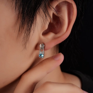 Boucle d'oreille fermeture éclair en argent avec zircon bleu sur modèle et fond noir