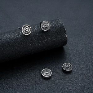 Vintage lion head relief earrings in silver-toned oxidized metal on a dark background
