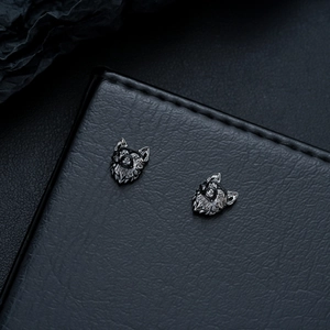 Macro shot of punk wolf head magnetic earrings in gun black finish on leather surface