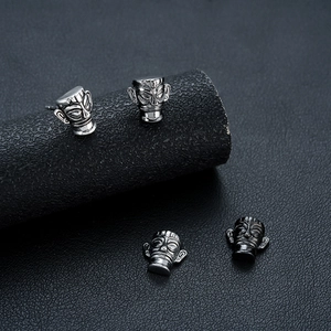 Sanjingdui mask stud earrings in silver and black metal finishes shown on a black display