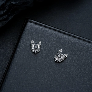 Detailed close-up of a wolf head earring with vintage oxidized finish on black leather