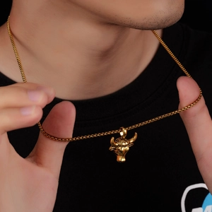 Gros plan d'un collier pendentif tête de bœuf doré au fini poli sur un mannequin